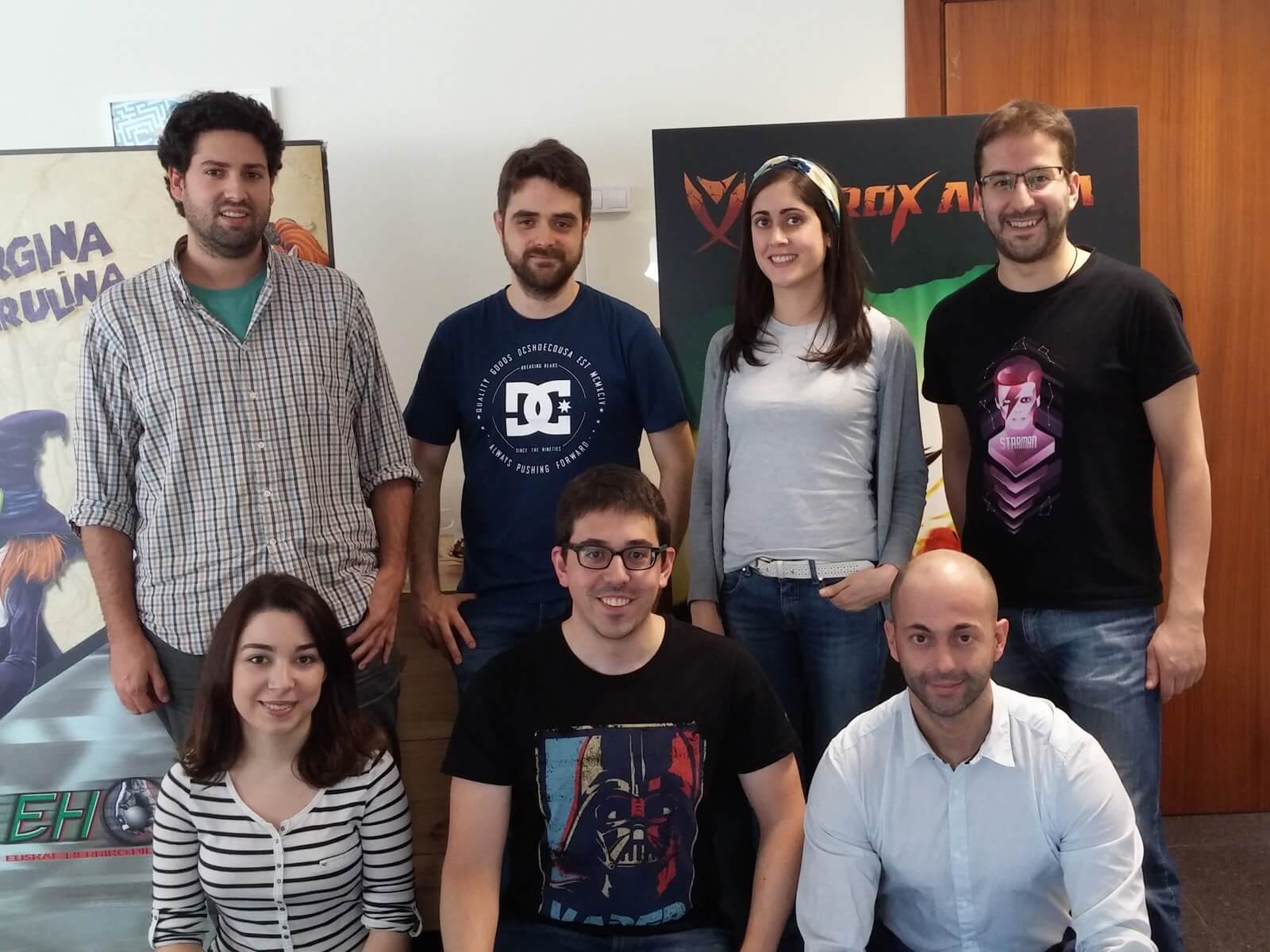 El equipo de Binary Soul posando frente a carteles que representan personajes de sus juegos.