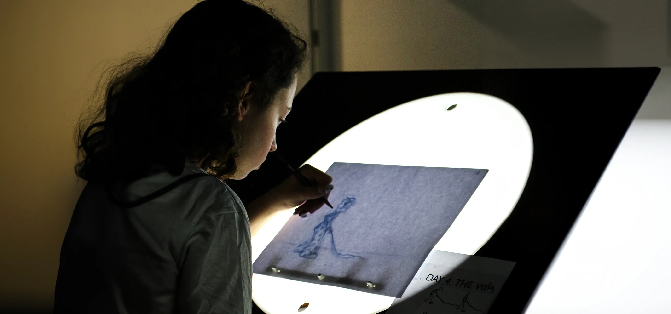 Girl working on a lightbox, tracing an animation frame