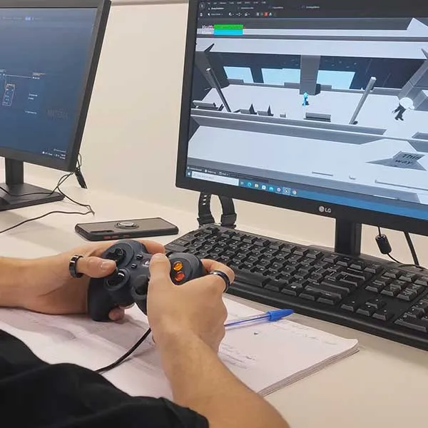 A student uses a controller to test an early build of a video game he is working on