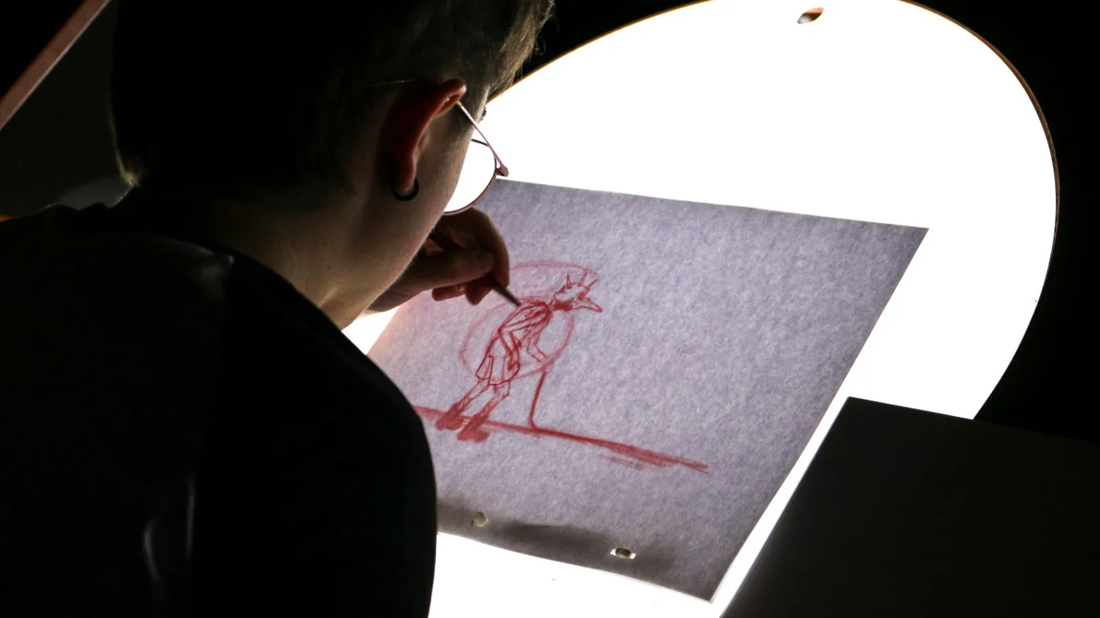 A boy drawing a frame of his animation on a lightbox