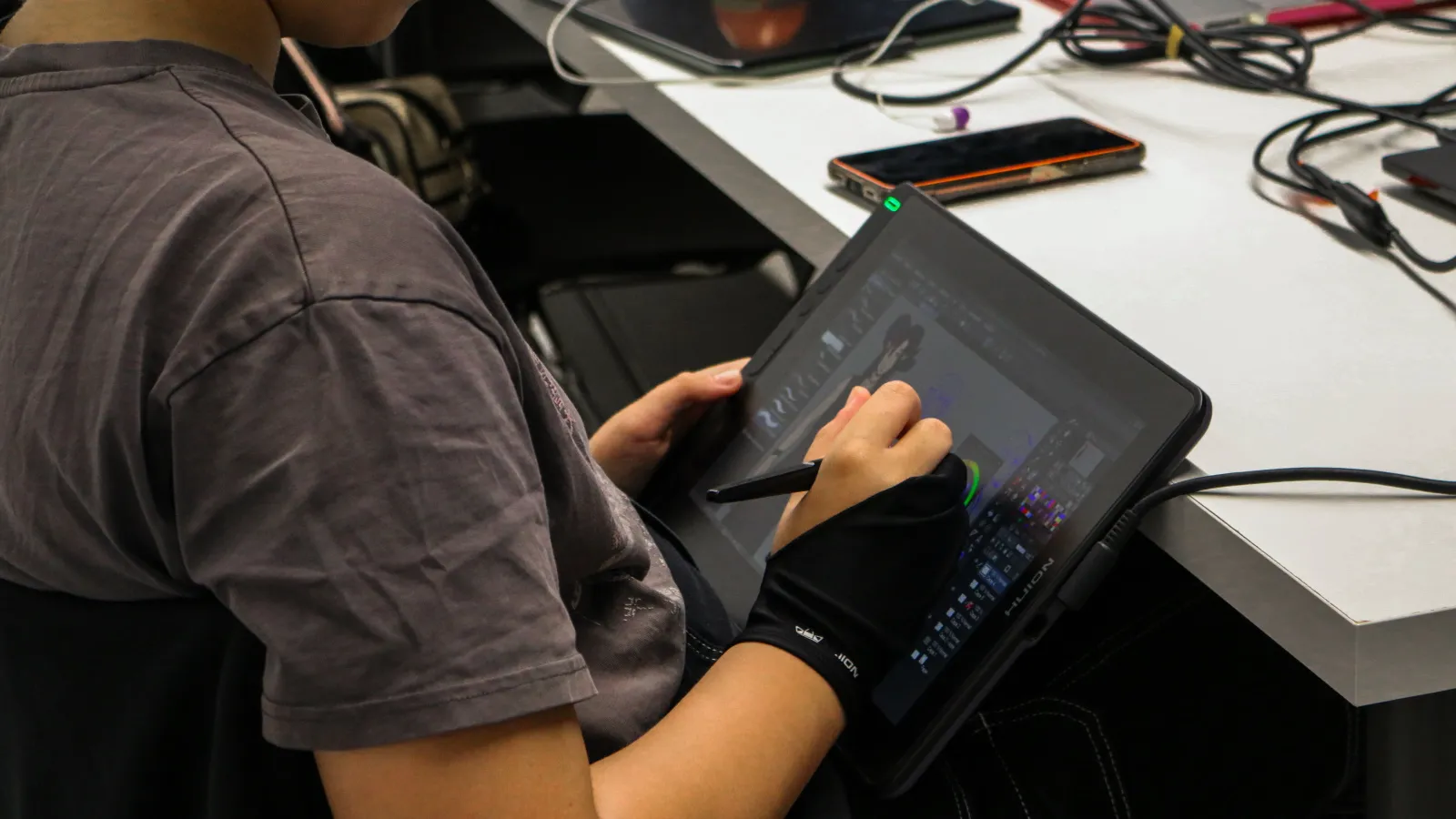 Un estudiante usando un guante de dibujo y una tableta gráfica trabajando en la tarea