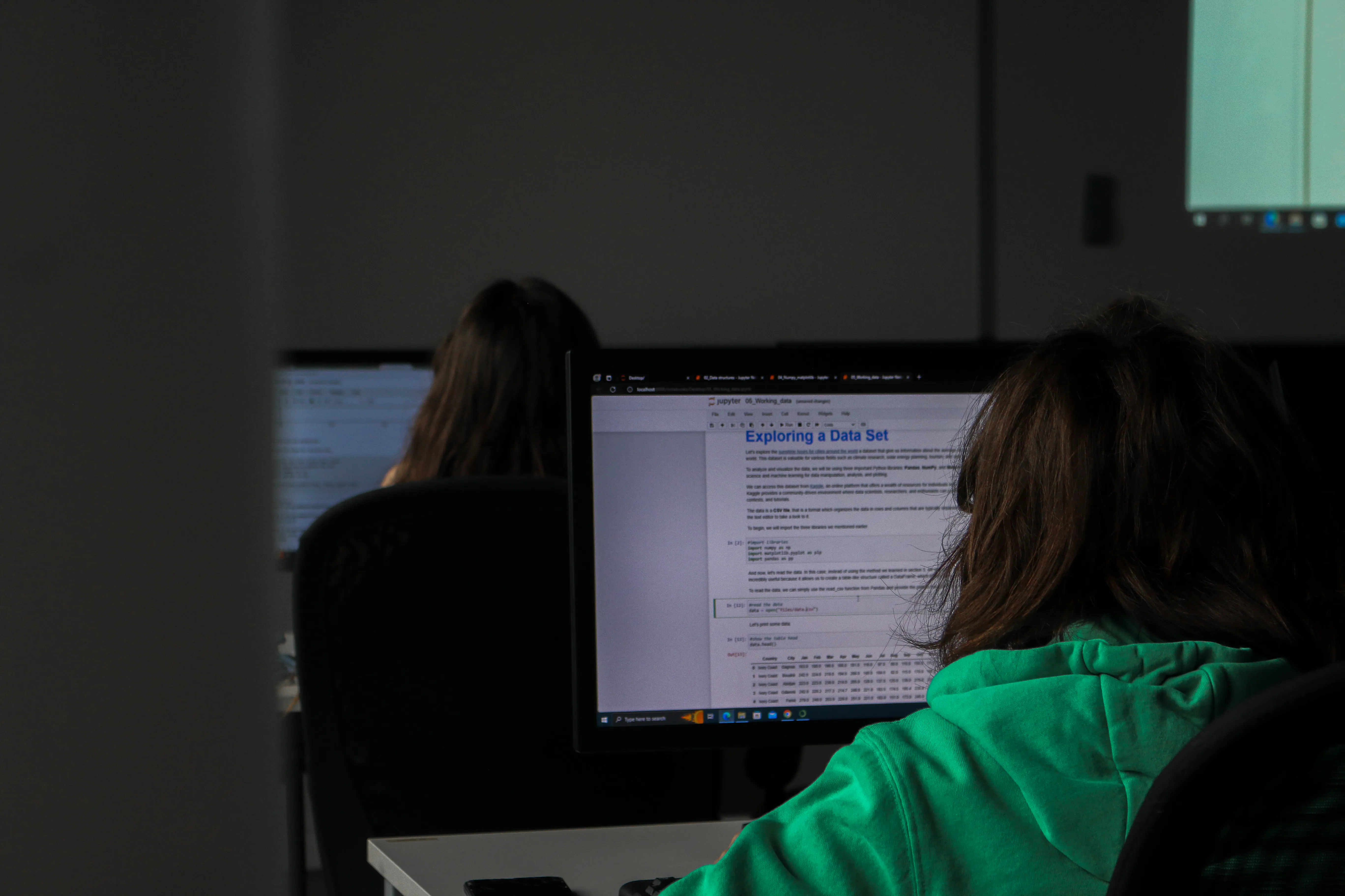 Una chica mirando su computadora trabajando en un código en Python.