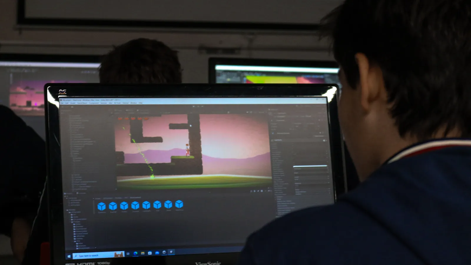 La pantalla muestra un fotograma del videojuego que el estudiante está desarrollando. Se ve un personaje y plataformas.
