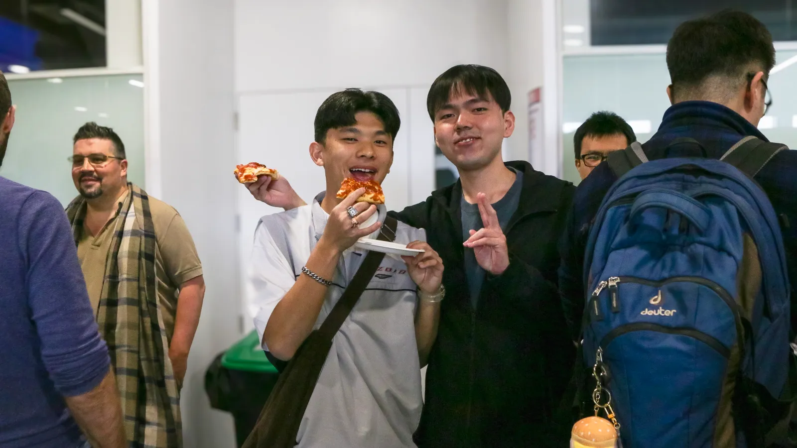 Dos estudiantes de Singapur muestran la pizza que están comiendo mientras conocen el campus de Europa