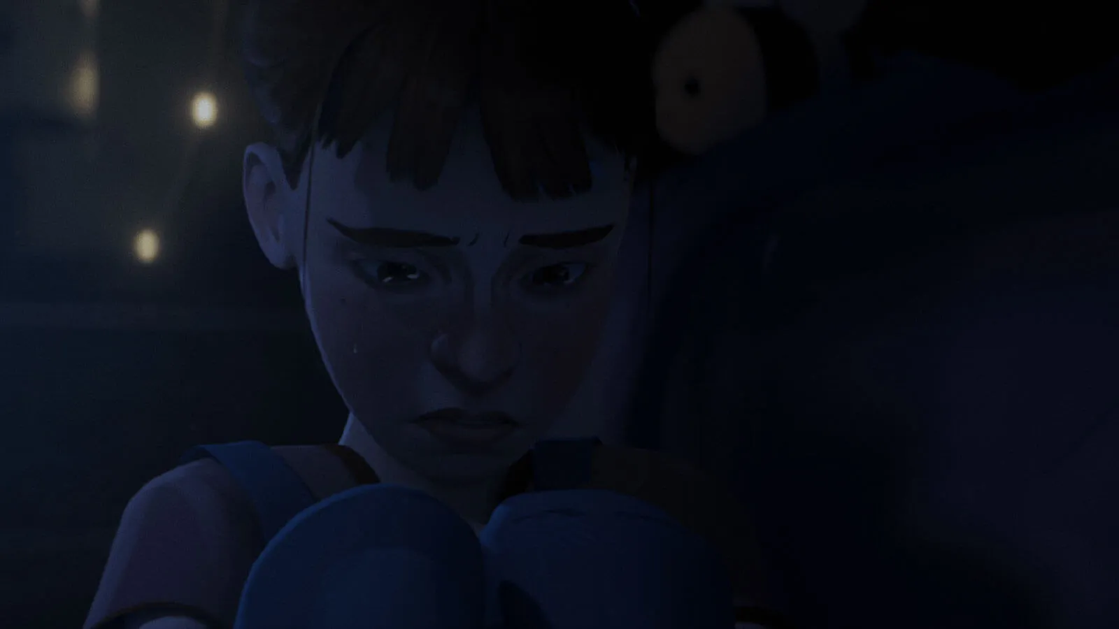 Close-up of a girl crouched and crying at night.