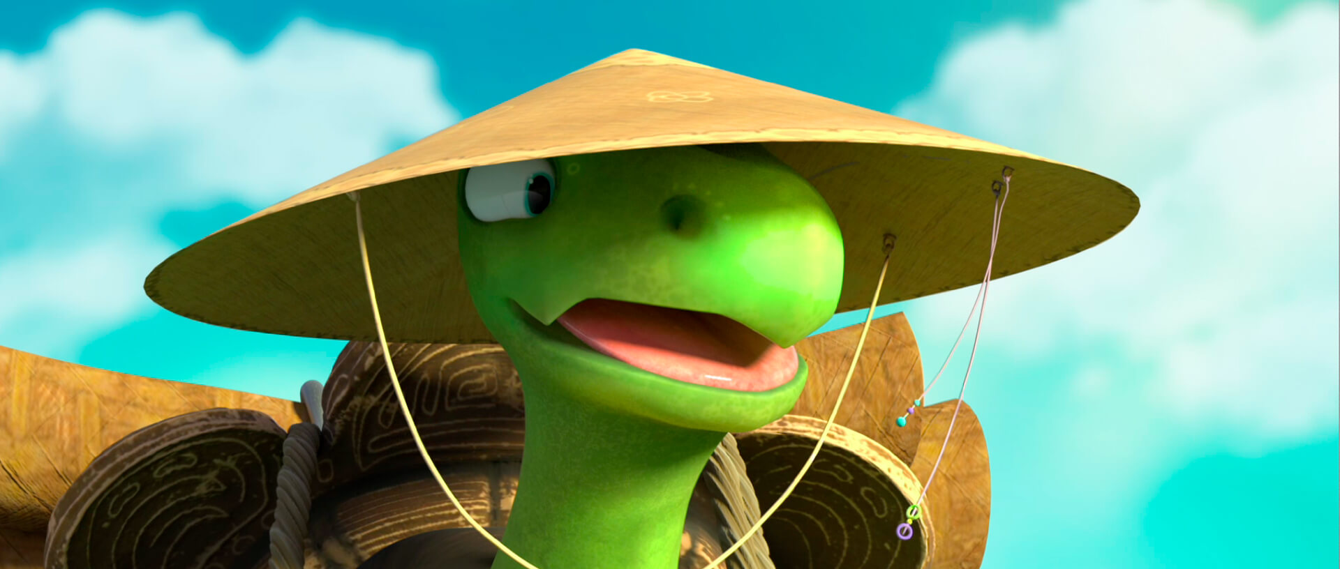 Close-up of smiling turtle character in a conical hat, against a blue sky with clouds.