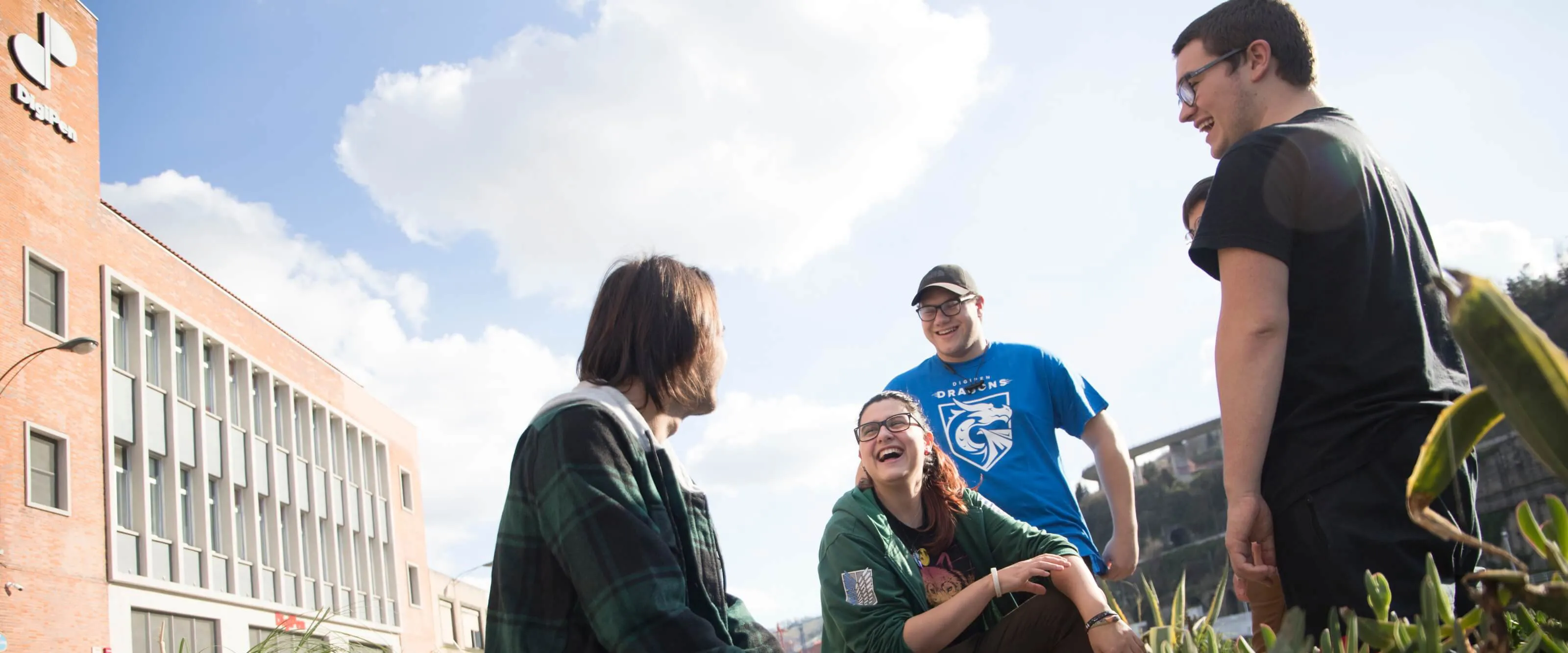 Cinco estudiantes disfrutan del aire libre justo afuera del edificio de DigiPen Europe-Bilbao.