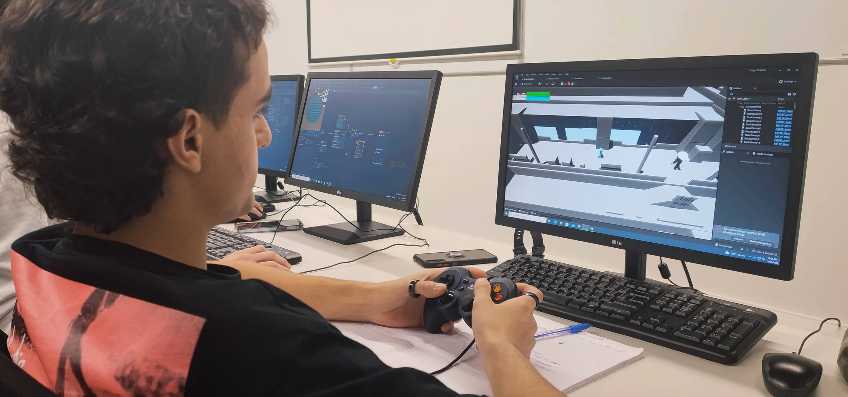 A student playtests an early version of a game while using a controller and looking at a monitor