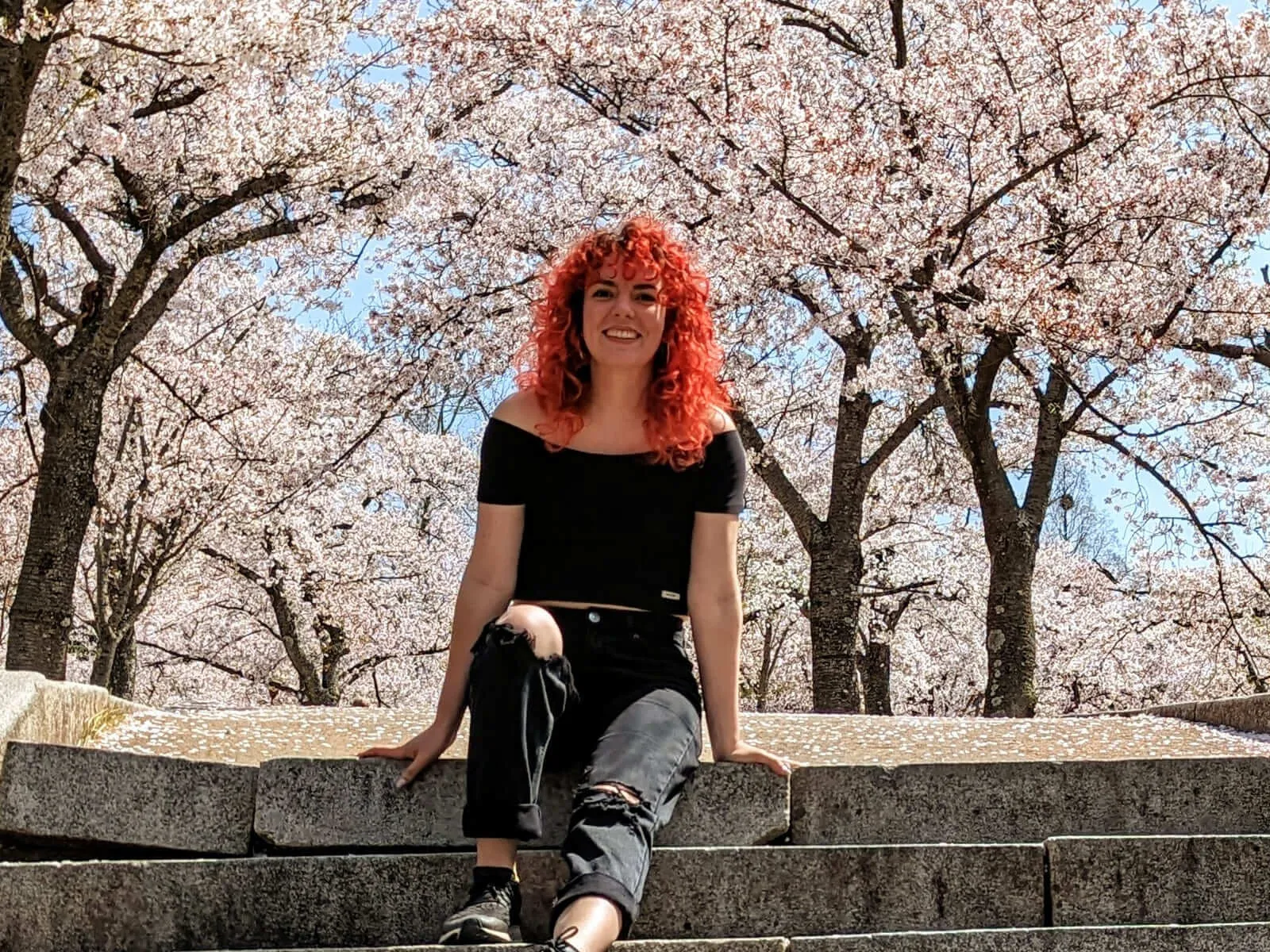 DigiPen graduate Marina Bordona standing in a beautiful cherry blossom garden.