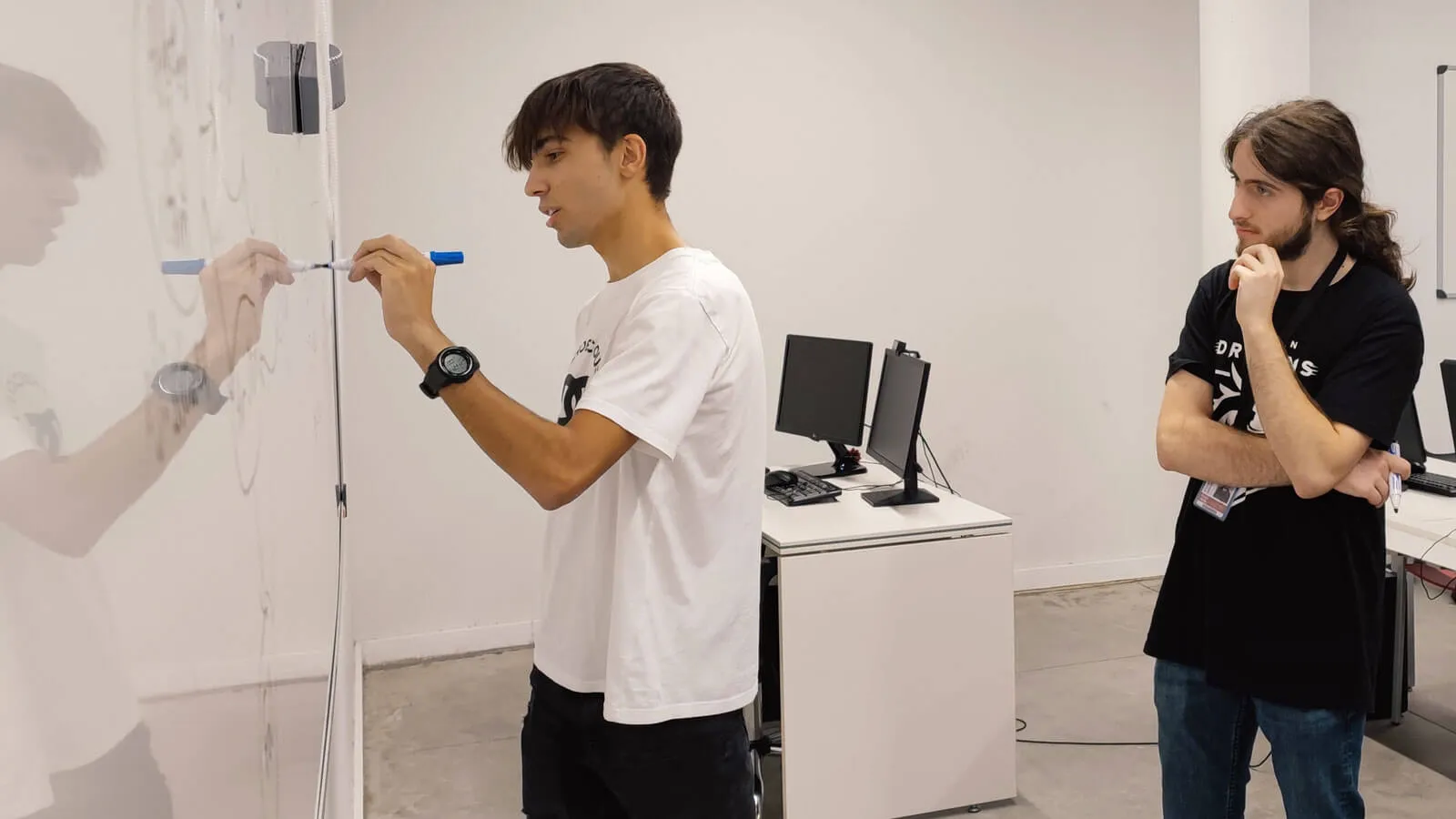 A Bilbao student draws on a drawing board as another watches.