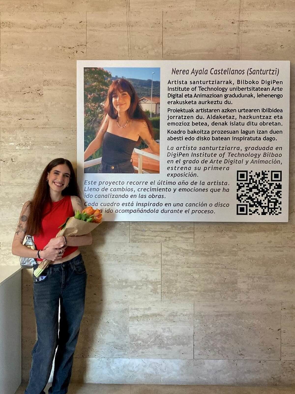 Nerea Ayala Castellanos posing beside a poster describing her art project.