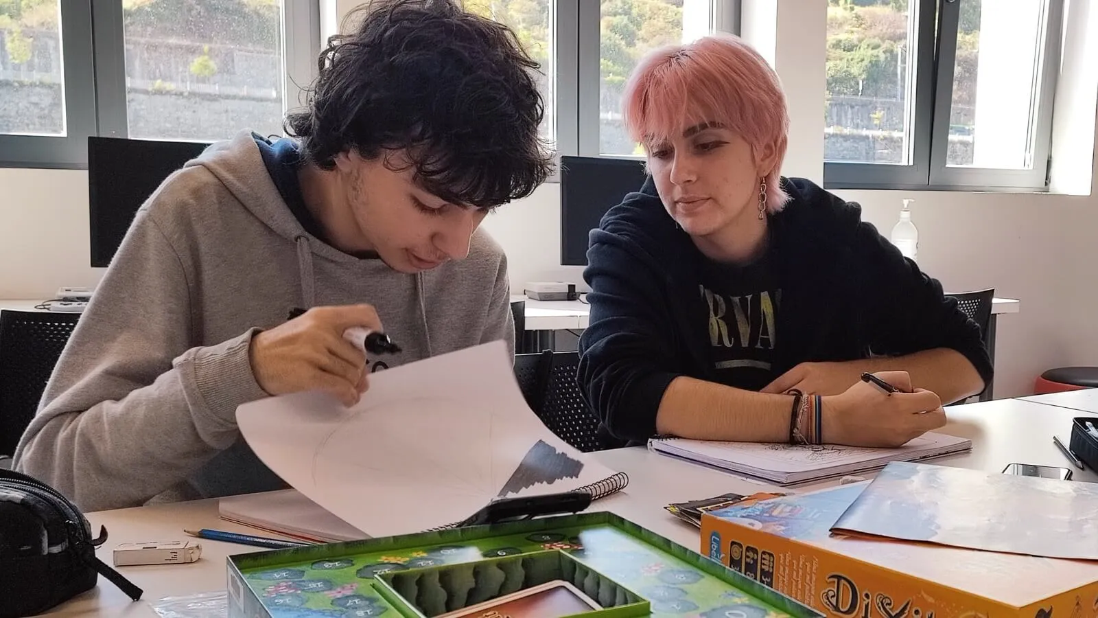 Dos estudiantes de BFA sentados en una mesa colaborando en un boceto artístico.