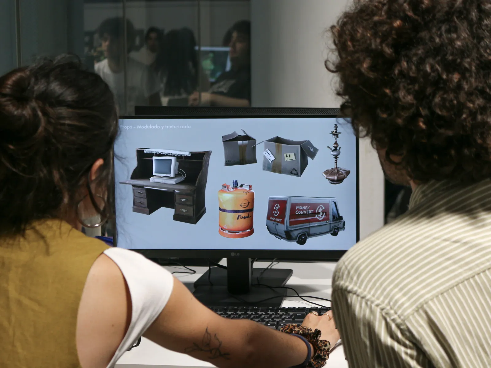 BFA graduate presents portfolio on a computer screen to one of the professionals consisting of 3D models of props