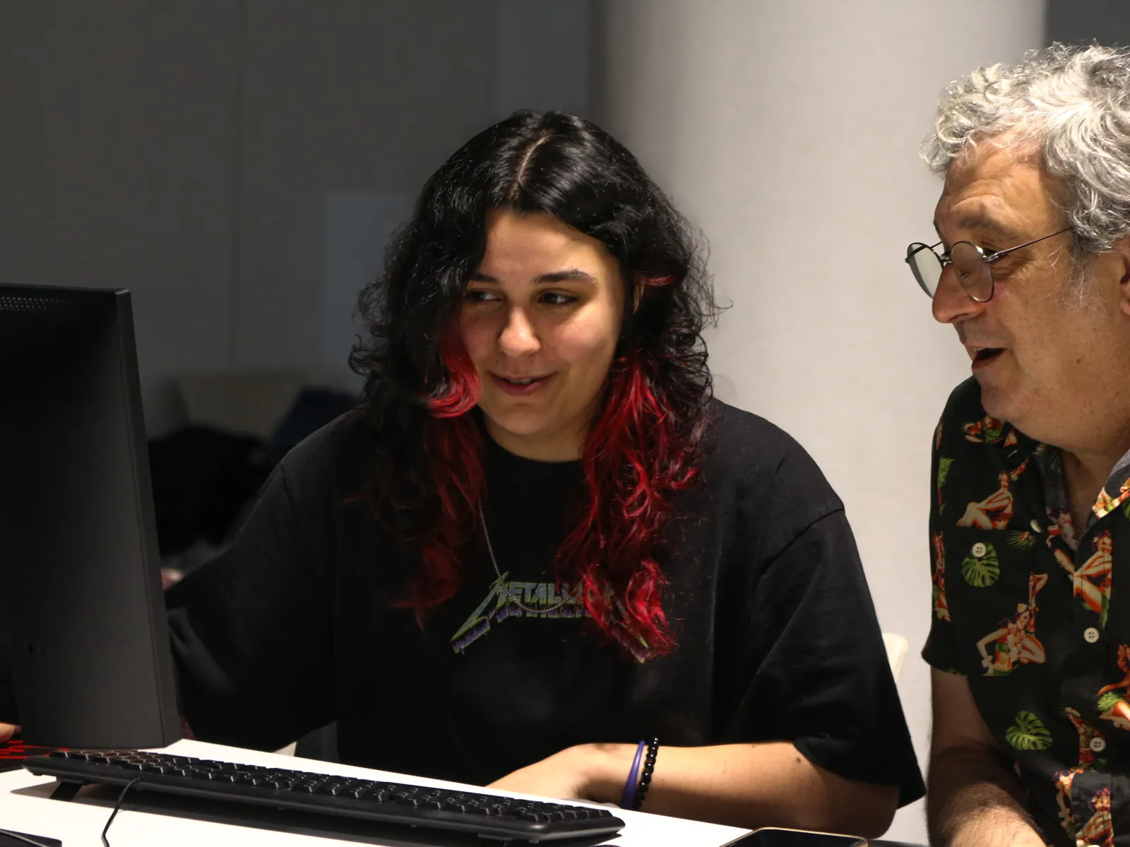 A graduate shows her work to an industry professional on a desktop computer.