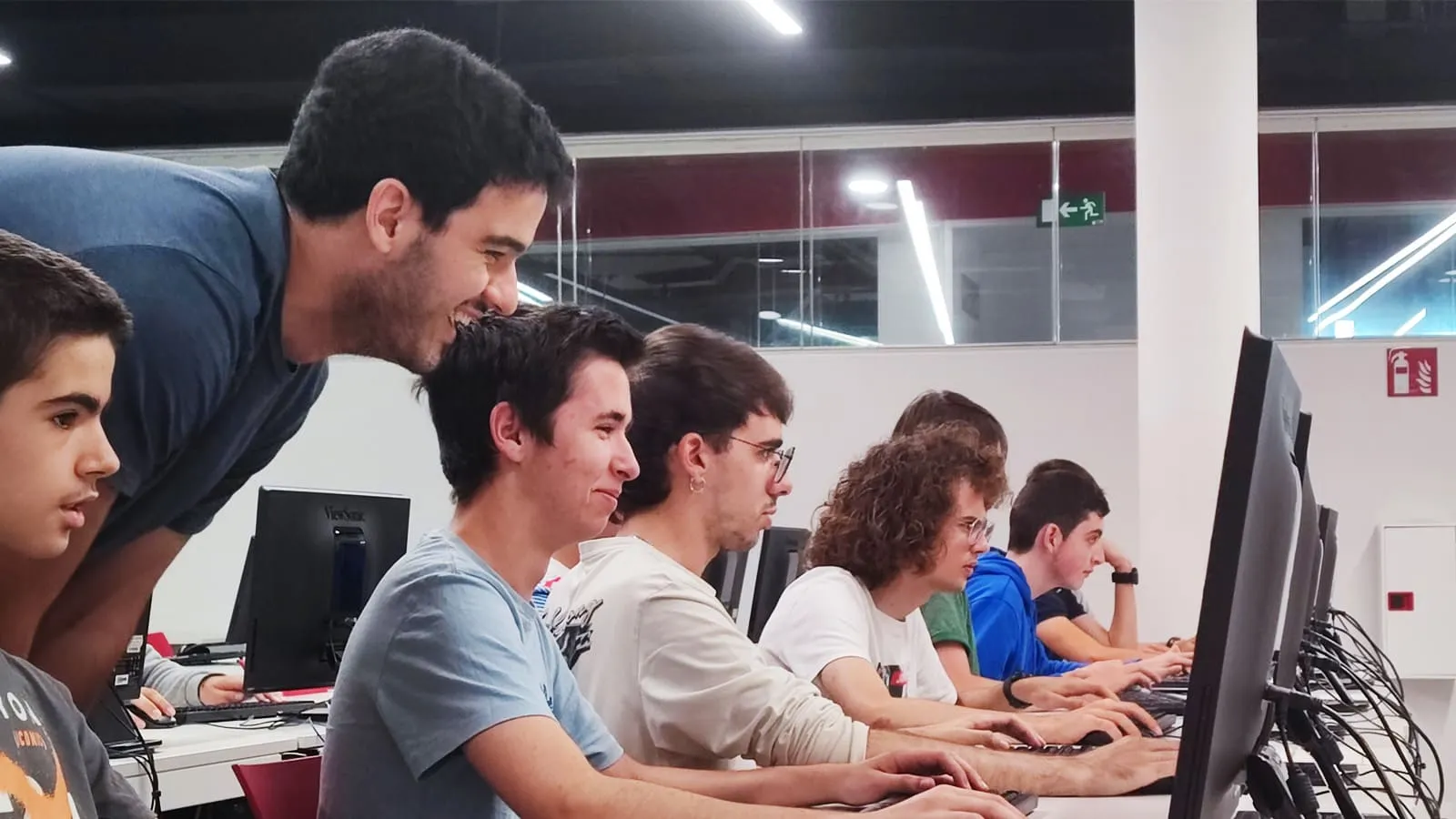 Teacher and group of students working in a classroom at DigiPen Europe-Bilbao with their respective computers.