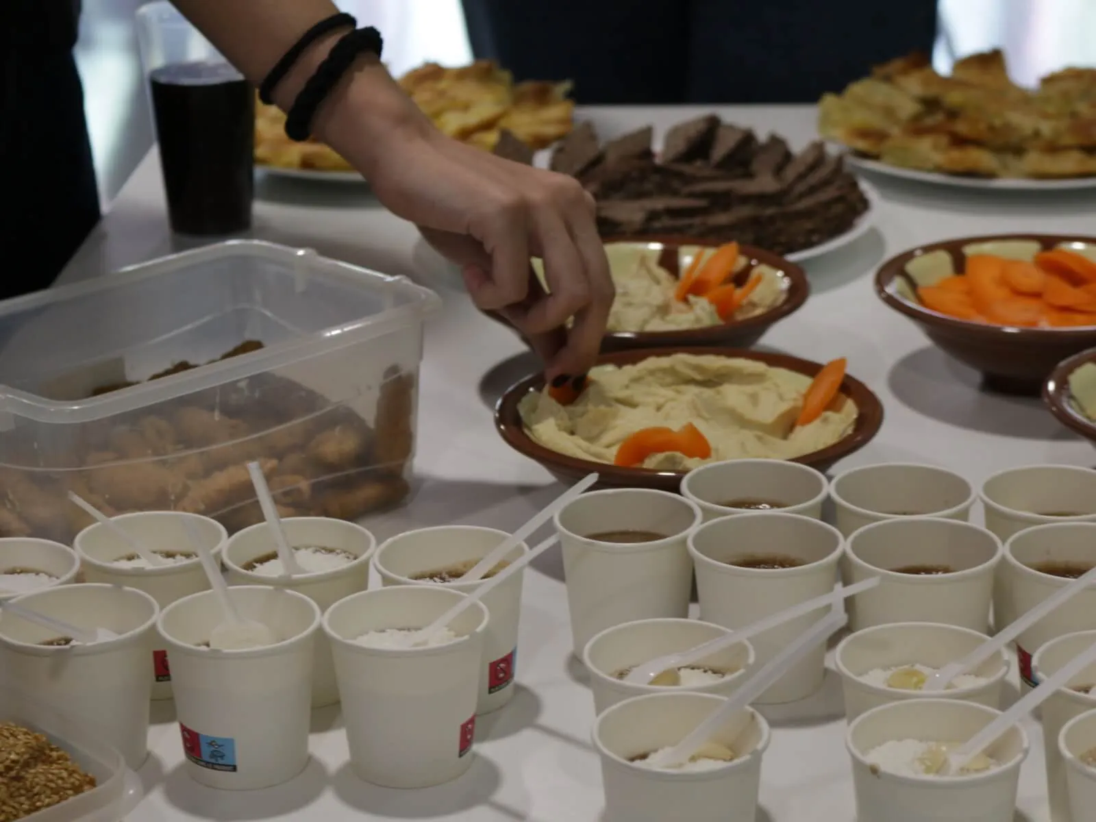 Una mesa repleta de comida libanesa, que incluye hummus, zanahorias y varios postres.