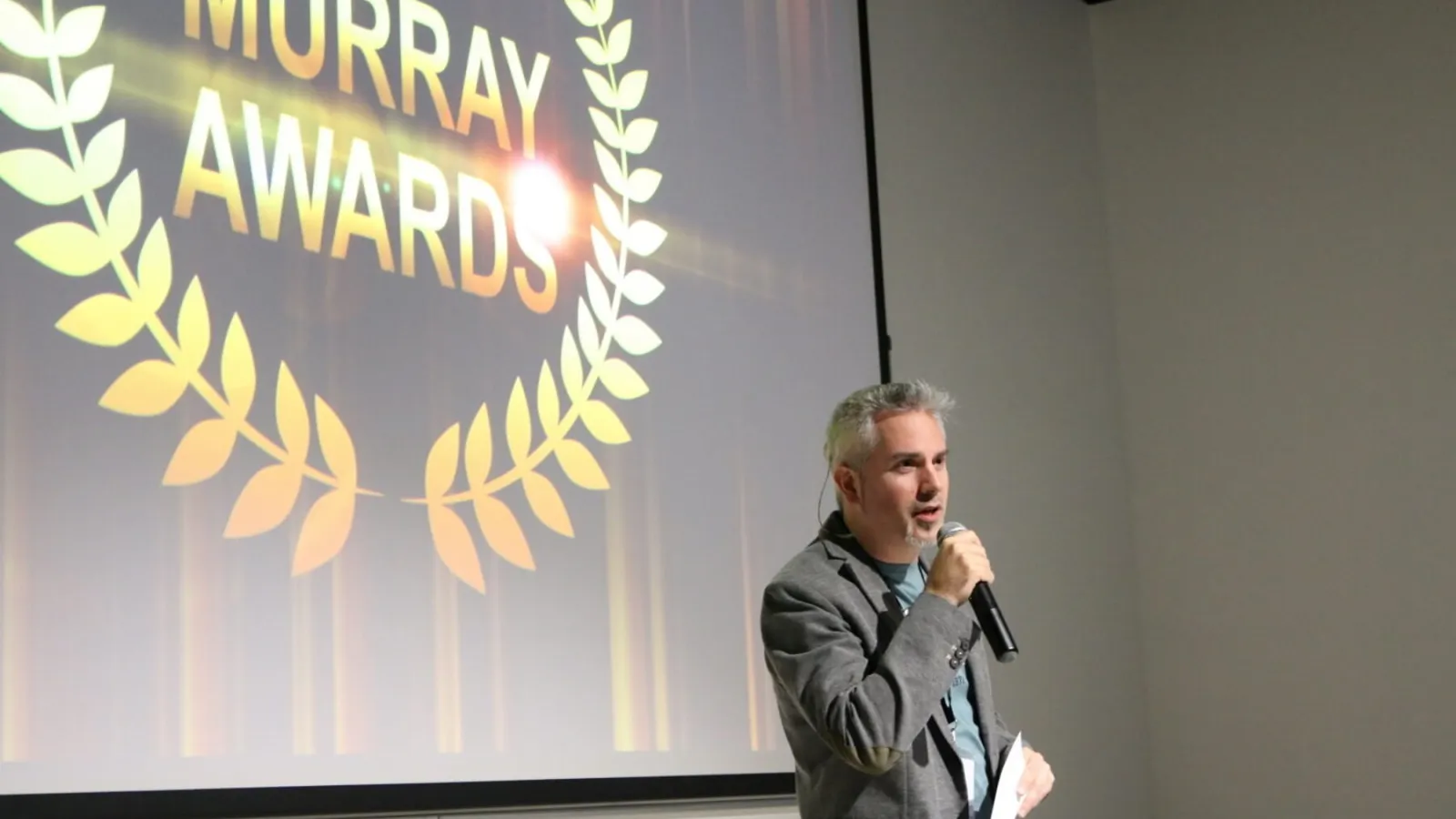 The presenter of the awards show uses a microphone to speak.