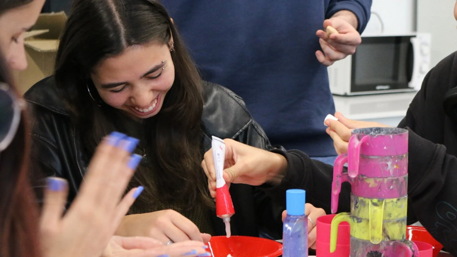 A DigiPen Europe-Bilbao student smiles while mixing makeup for realistic wound effects during the Halloween Makeup Workshop.