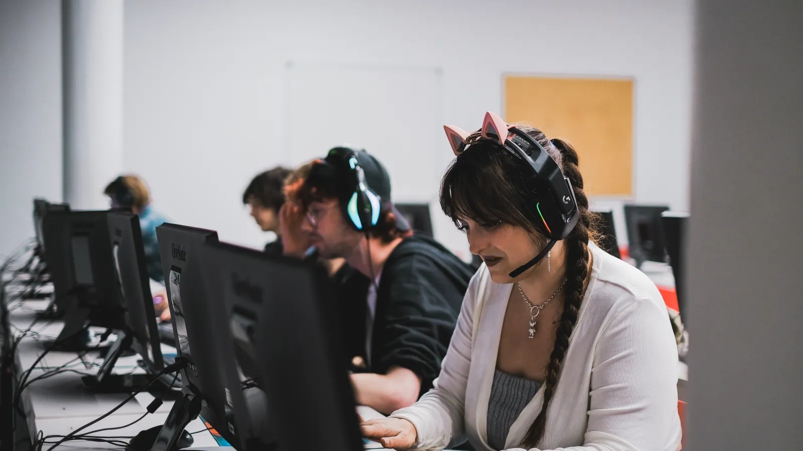 A student wearing a gaming headset, playing Valorant on a computer in a classroom setting at DigiPen Europe-Bilbao.