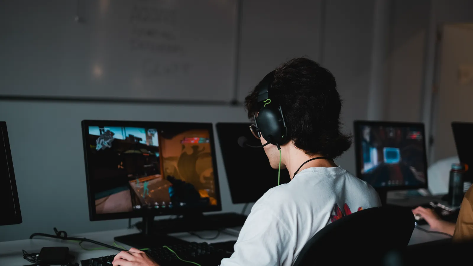 A student wearing a gaming headset with cat ears intensely focused on a computer screen during a Valorant tournament at DigiPen Europe-Bilbao.