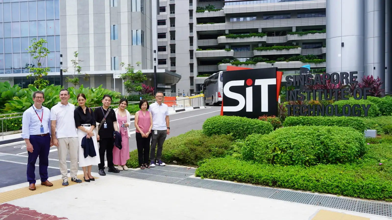 Representantes de DigiPen Europe-Bilbao posan frente al edificio principal del Singapore Institute of Technology junto a su personal, con un entorno lleno de vegetación.