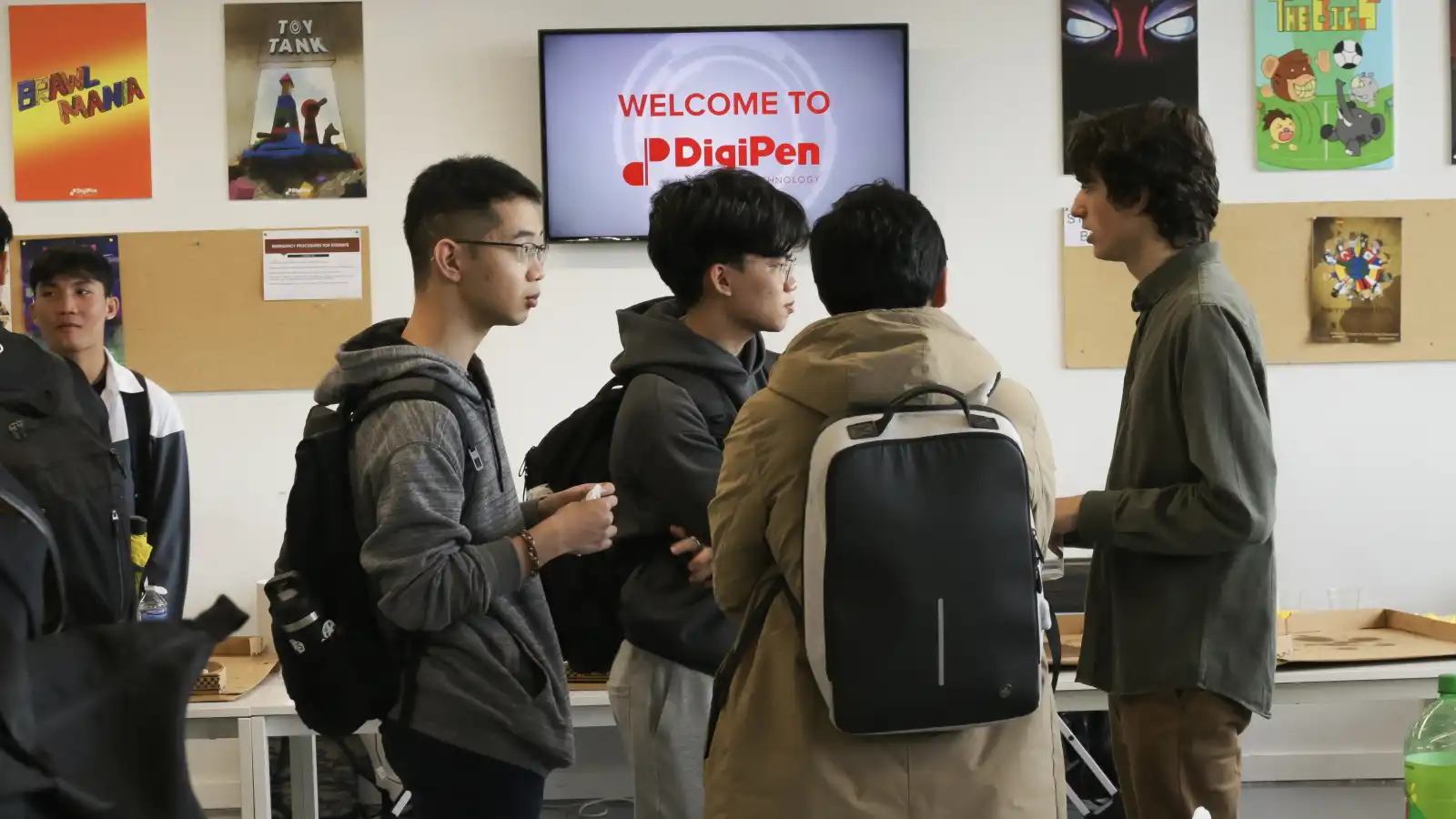 Estudiantes de intercambio de Singapur conversando en el campus junto a un letrero de bienvenida de DigiPen.